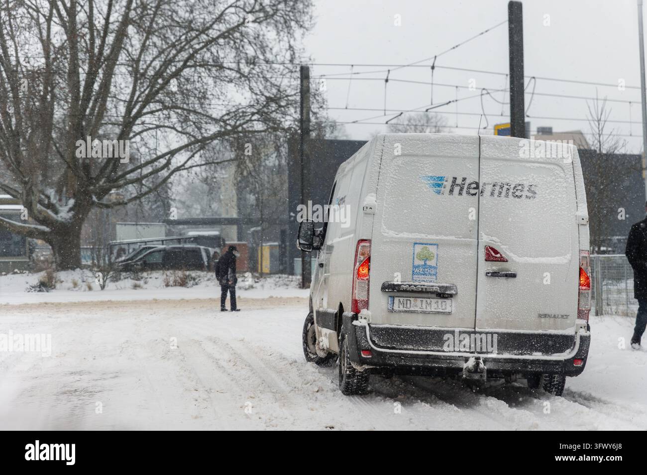 Magdebourg, Allemagne – 9 janvier 2026 : Un camion de livraison Hermes couvert de neige roule sur une route boueuse pendant une forte chute de neige. Défis météorologiques hivernaux Banque D'Images