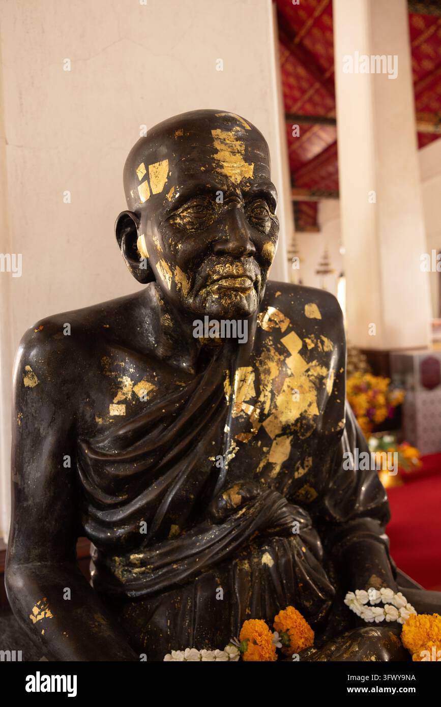 Bangkok, Thaïlande - 1er février 2026 : Une statue en bronze d'un moine assis ornée de feuille d'or se trouve à l'intérieur d'un temple. Banque D'Images