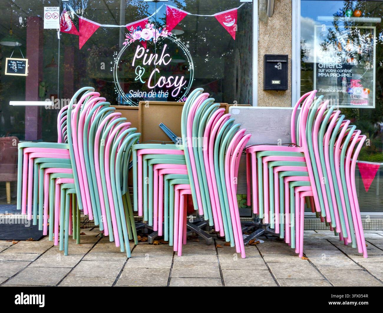 Piles de chaises de café roses et vert pâle sur la terrasse du café / salon de thé "Pink & Cosy" - La Roche Posay, Vienne (86), France. Banque D'Images