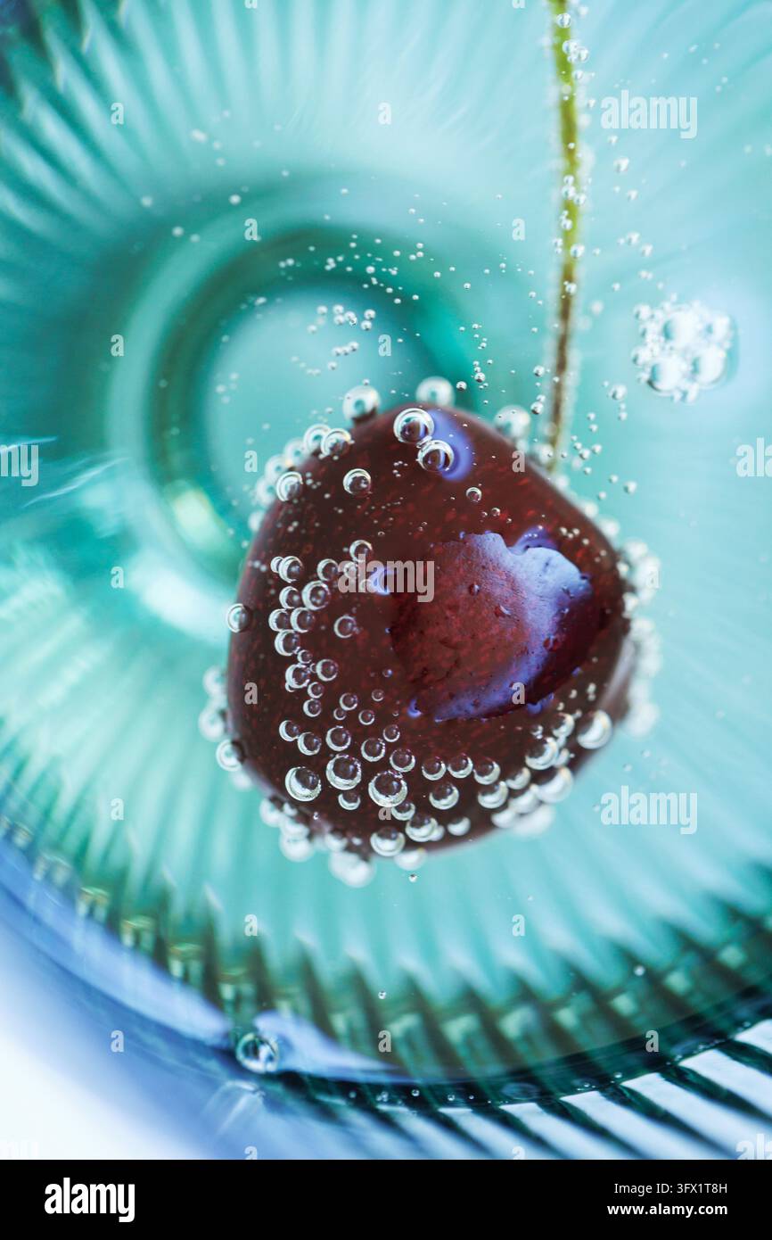 Macro abstraite de cerise avec bulles montantes dans un verre Banque D'Images