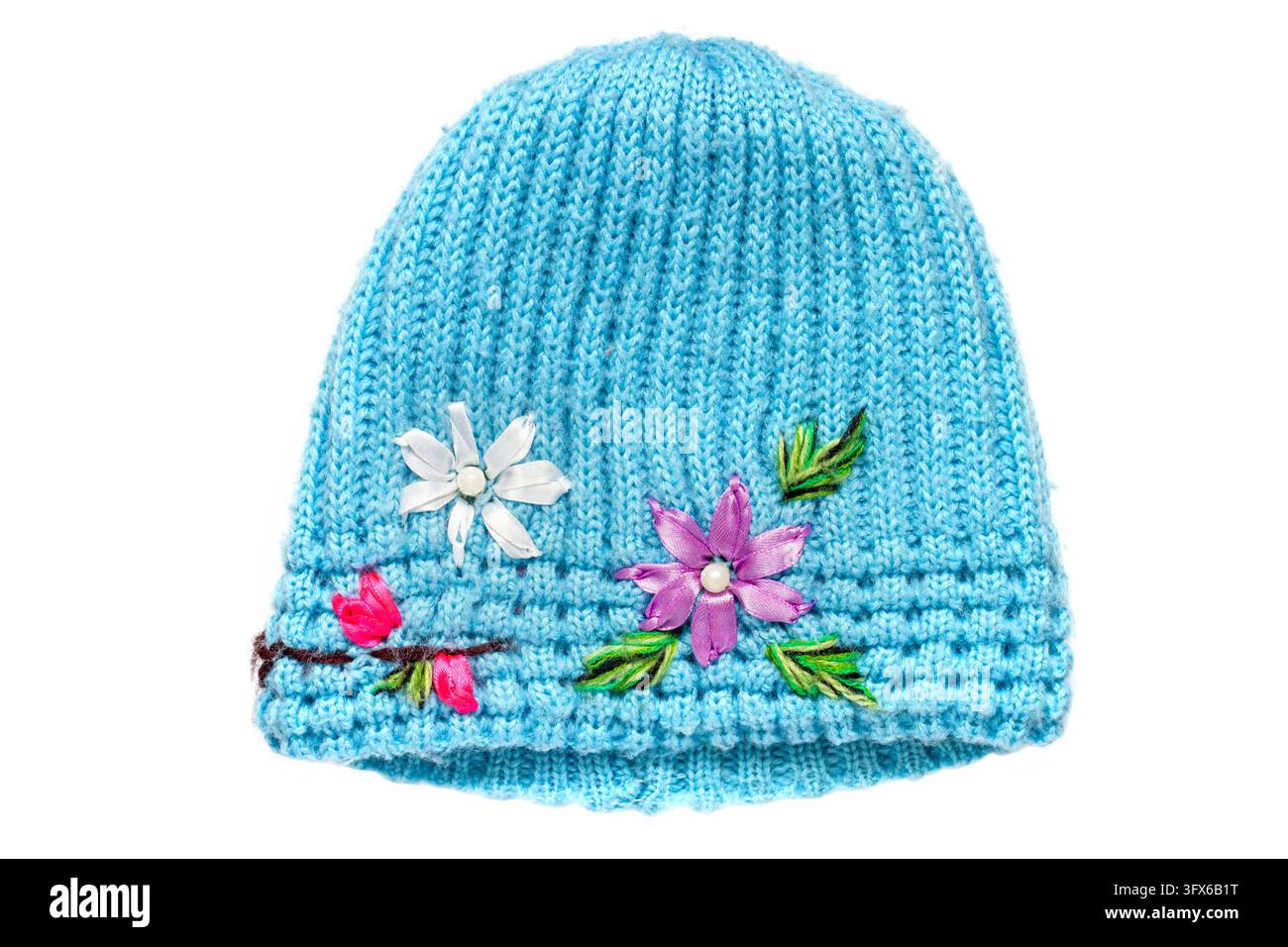 Chapeau tricoté bleu décoré de fleurs sur fond blanc. Chapeau chaud en gros plan. Banque D'Images