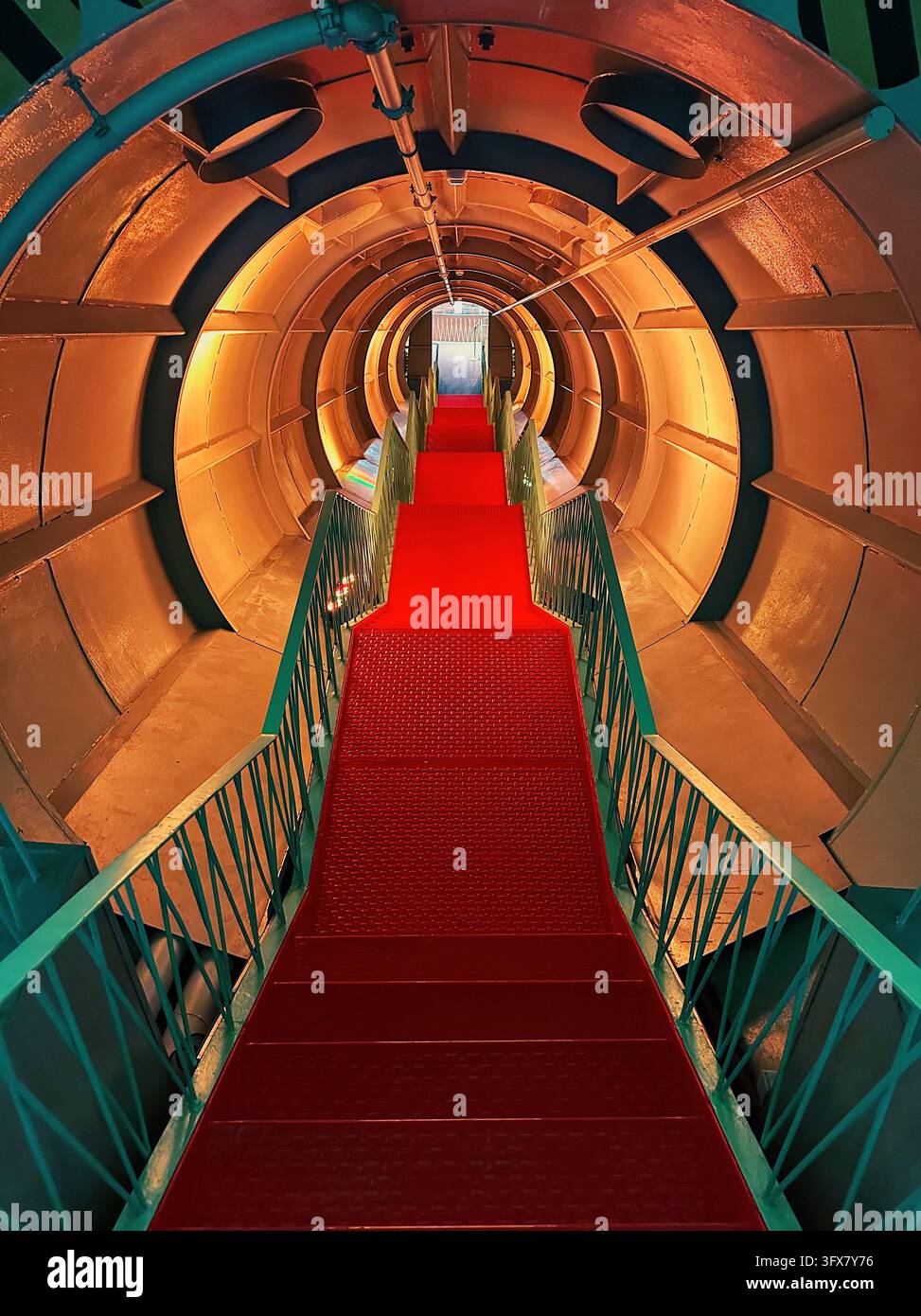 Vue intérieure symétrique d'un tunnel circulaire rétro-futurist avec des escaliers rouges et des rampes vertes à l'intérieur de l'Atomium. Banque D'Images