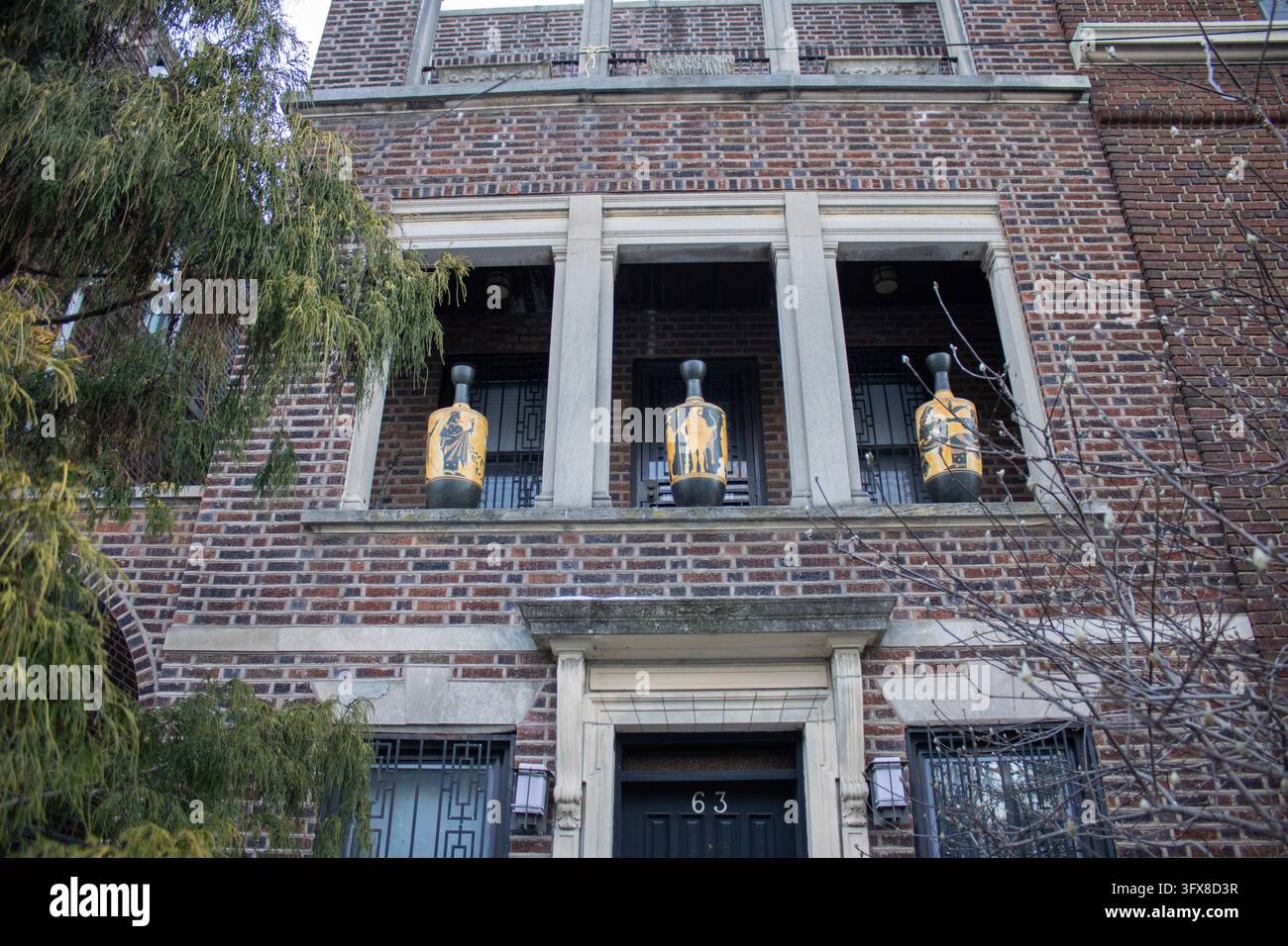 Brooklyn, NY – 21 janv. 2024 : Maison en briques brunes avec des urnes ornementales placées dans des niches de fenêtres encastrées et un arbre à côté, Brooklyn en hiver. Banque D'Images