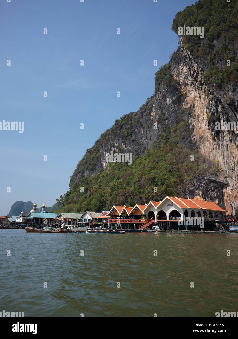Restaurant et mosquée de village sur pilotis sous une falaise de calcaire, Thaïlande. Banque D'Images