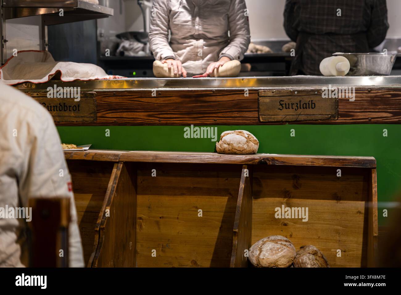 Le boulanger façonne la pâte à pain fraîche à la main derrière un comptoir en bois dans un stand de nourriture traditionnelle allemande. Les pains croustillants et la poussière de farine mettent en valeur l'artisanat de la boulangerie Banque D'Images
