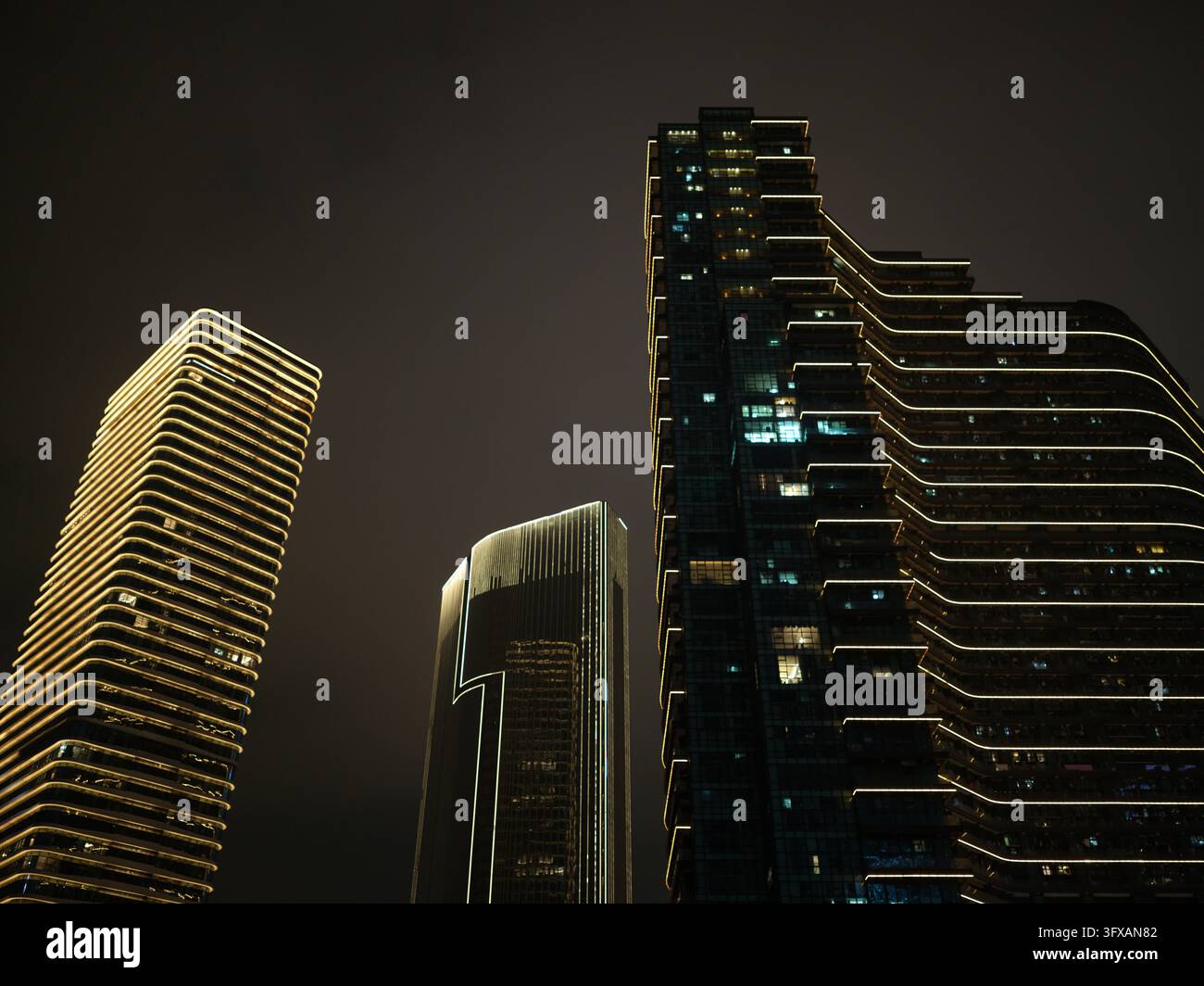 Trois gratte-ciel illuminés avec des lignes de contour lumineuses la nuit. Banque D'Images