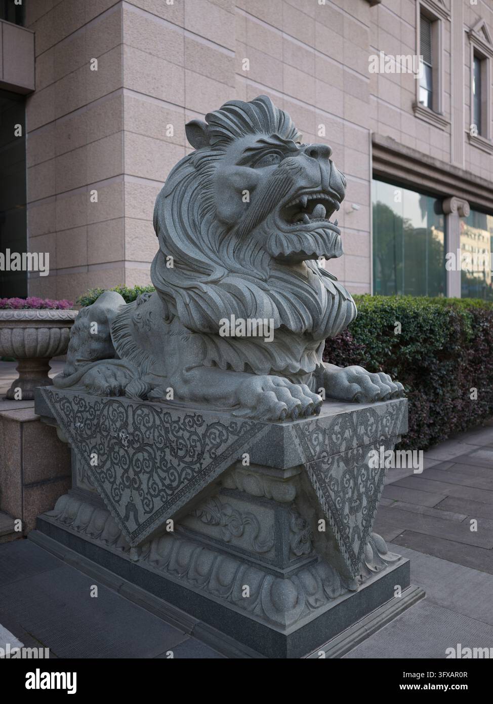 Statue de lion gardien en granit sculpté devant un bâtiment en pierre à Ningbo, Chine. Banque D'Images