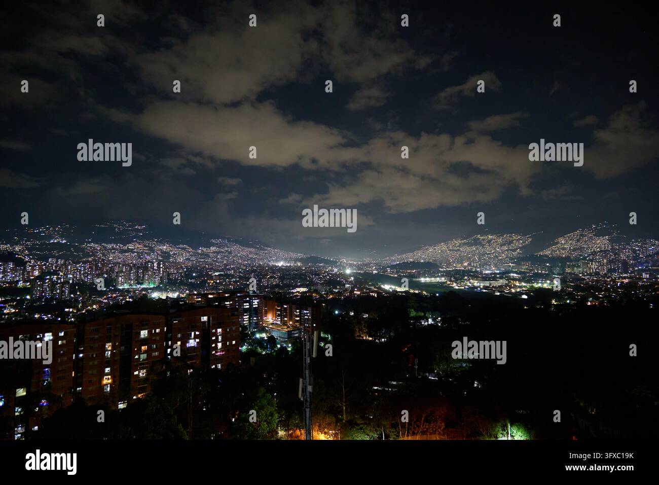 Les lumières de la ville de Medellín scintillent la nuit sous un ciel nuageux. Banque D'Images