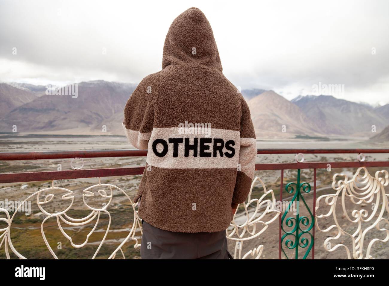Personne portant une veste polaire à capuche vue de dos regardant une vallée montagneuse depuis une terrasse, Ladakh, Turtuk, Inde Banque D'Images