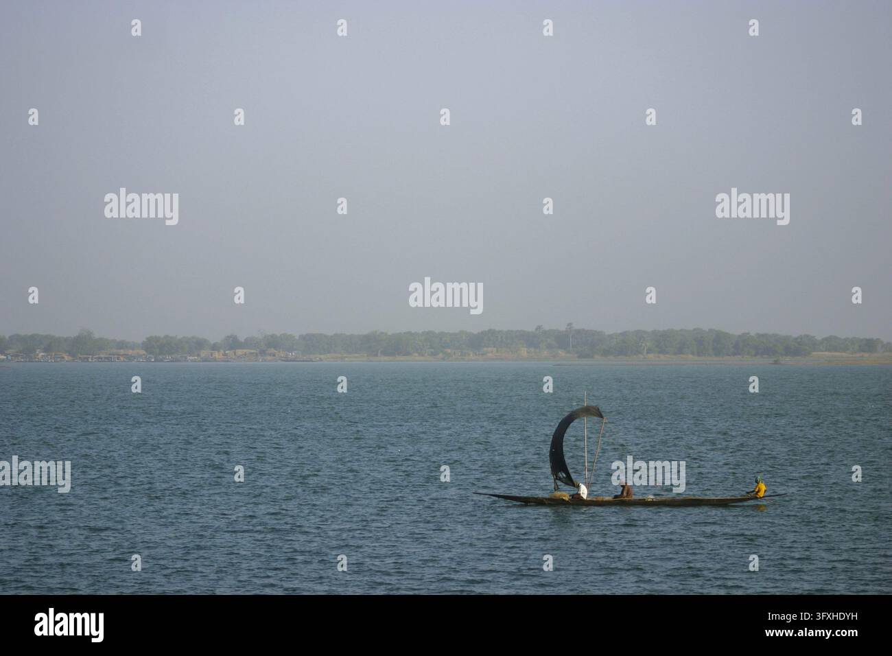 Pirogue traditionnelle avec une voile sombre traversant le large fleuve Niger sous un ciel brumeux, région de Segou, Segou, Mali Banque D'Images