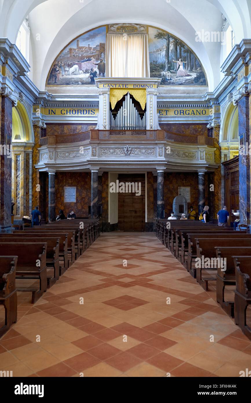 Nef centrale de la cathédrale de Città della Pieve, Ombrie, avec sol en terre cuite, bancs en bois, galerie d'orgue et fresques en lunette. Banque D'Images