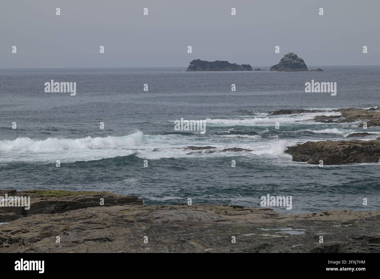 Vagues se brisant sur les rochers avec les îles Quies au loin, baie de Constantine, Cornouailles, Royaume-Uni, 26 avril 2026 Banque D'Images