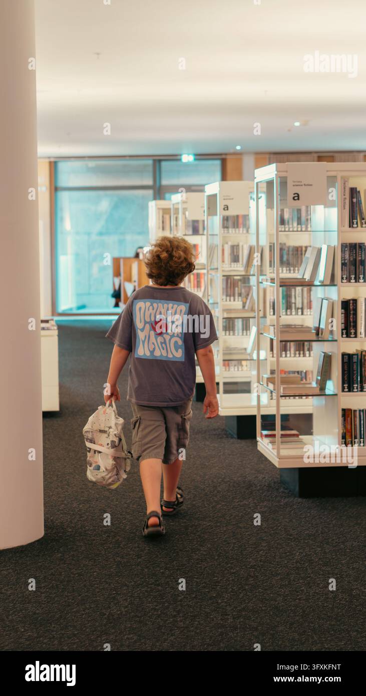 Amsterdam, Pays-Bas. 24 juillet 2026. Garçon portant un sac à dos entre des étagères de livres à la bibliothèque publique OBA Oosterdok. Banque D'Images