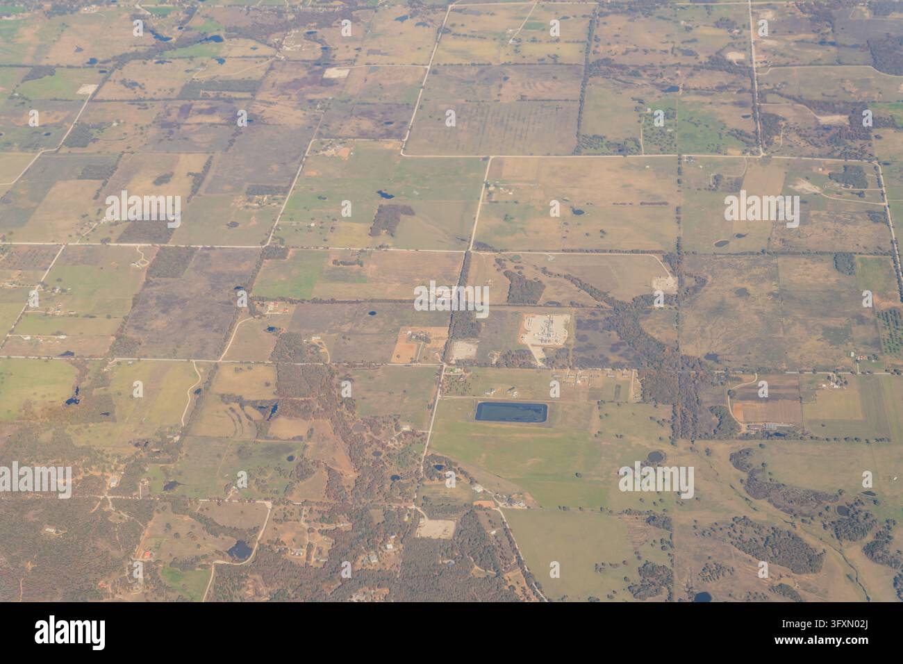 Vue aérienne d'un paysage rural présentant un réseau de routes, des champs en mosaïque, des arbres dispersés et de petits étangs. Banque D'Images