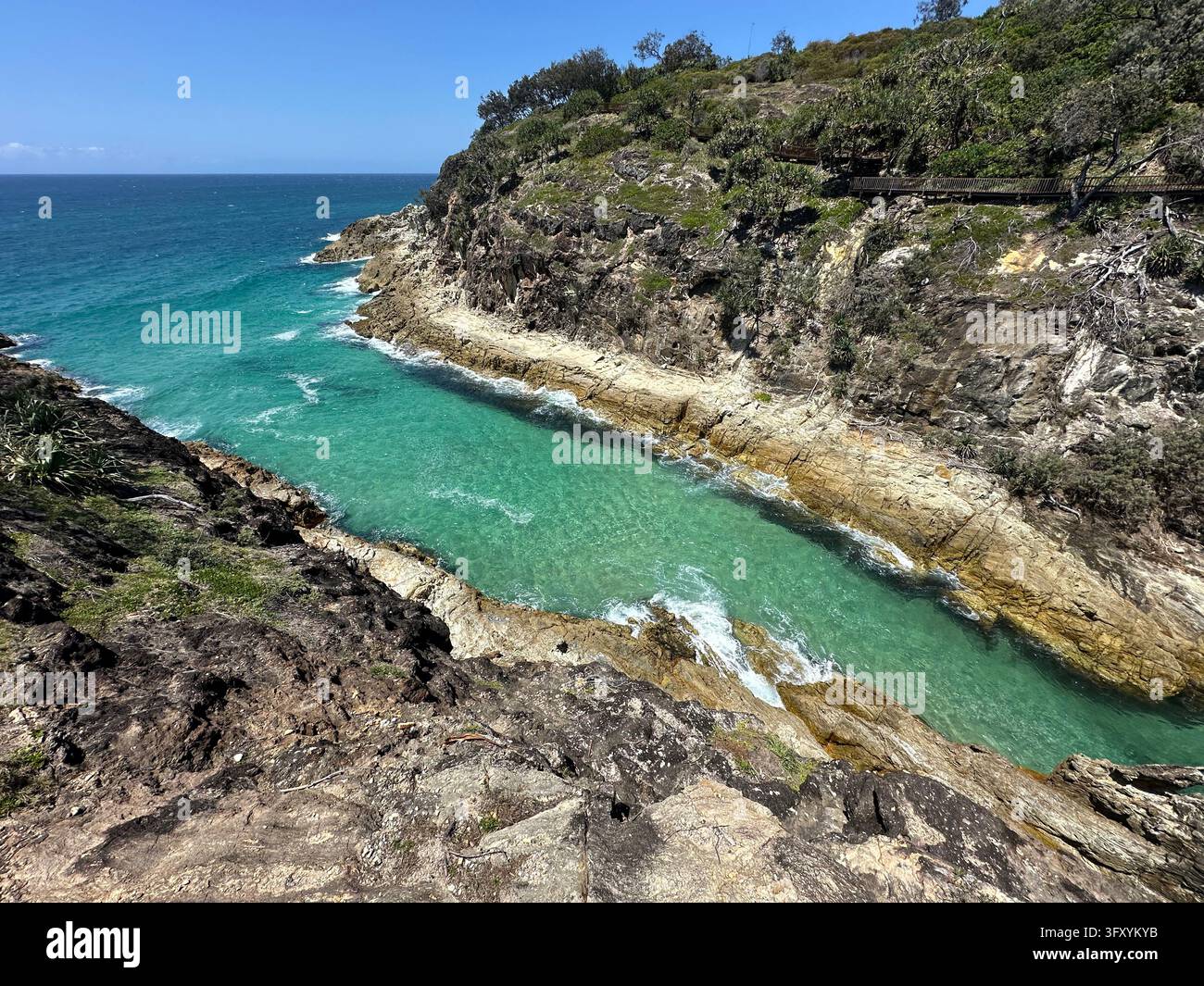 Eau turquoise déferlant dans une gorge rocheuse à Point Lookout, North Stradbroke Island (Minjerribah), Queensland, Australie. Banque D'Images