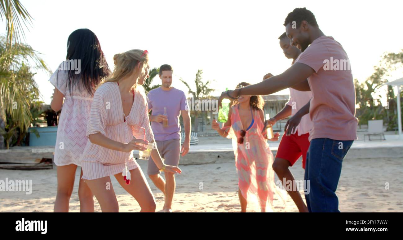 Groupe divers et joyeux d'amis dansant avec des cocktails à la plage. Vacances, temps libre, été et amitié. Banque D'Images
