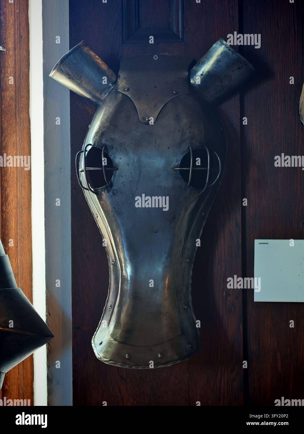 Coiffe en métal antique pour cheval, montée sur un mur en bois à l'intérieur du château médiéval de Reichsburg Cochem en Allemagne. Banque D'Images