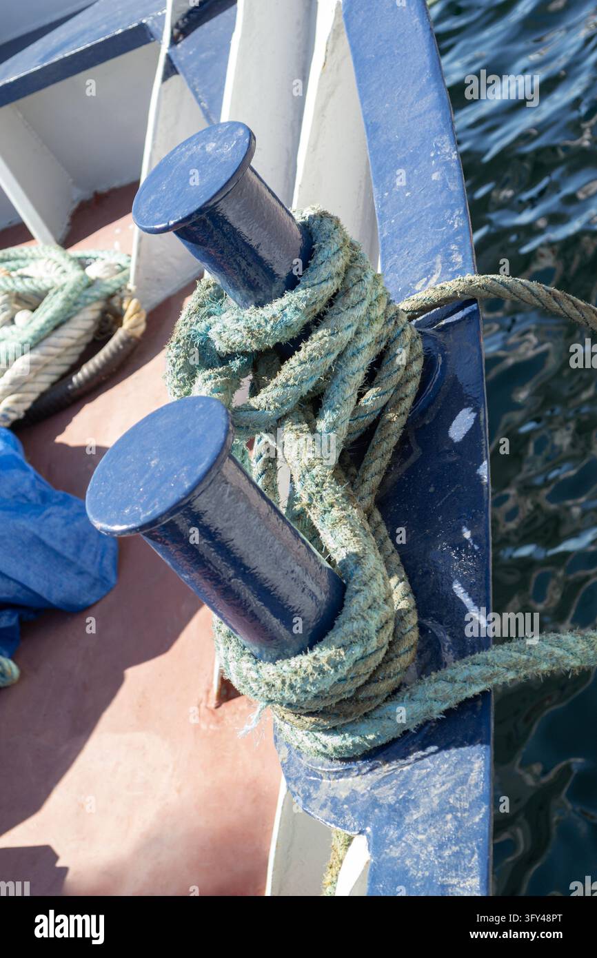 Corde d'amarrage usée enroulée autour de potelets bleus sur un bateau Banque D'Images