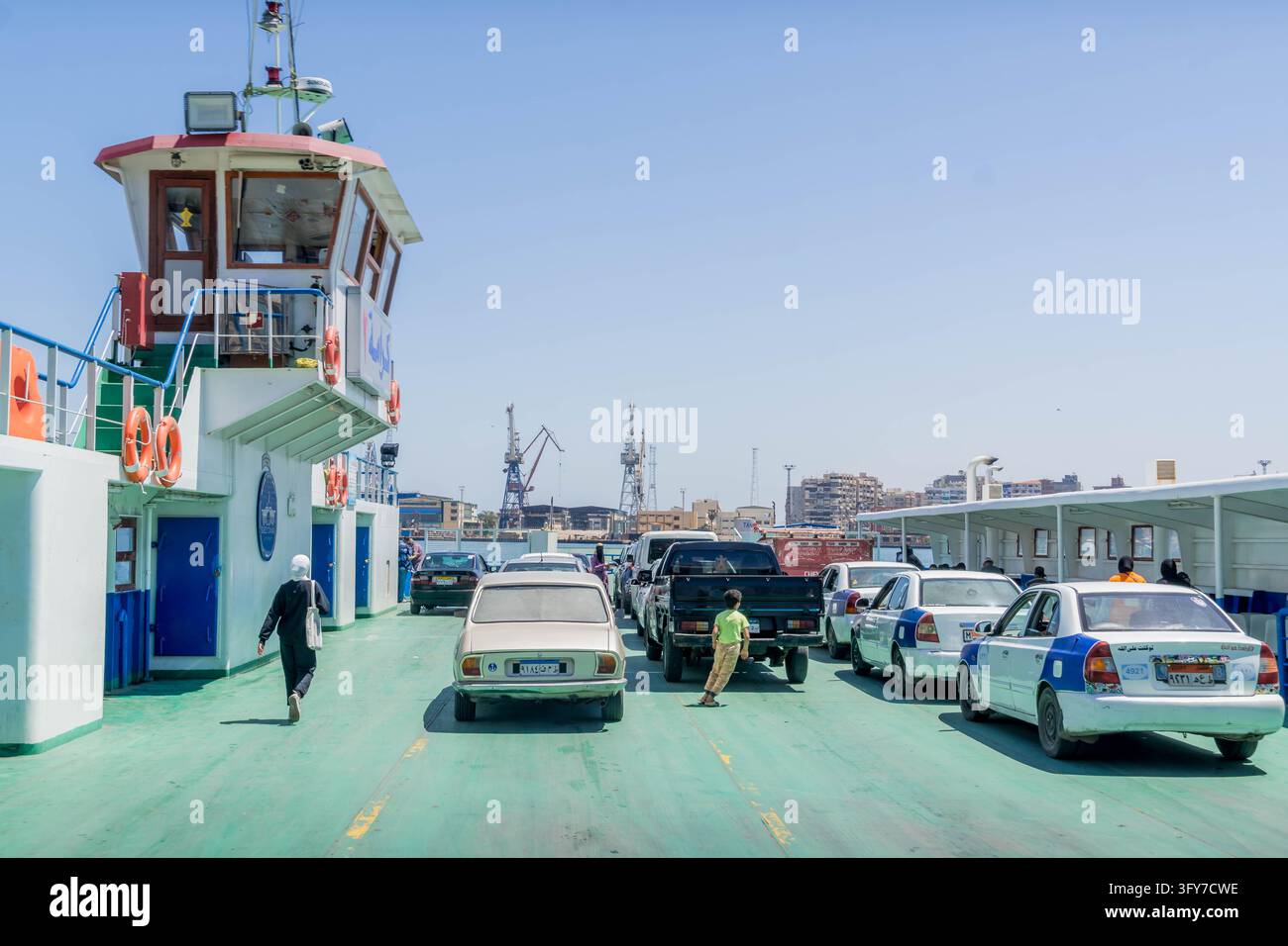 Véhicules et passagers embarquent sur un bac automobile reliant Port-Saïd et Port-Fuad à travers le couloir de transit du canal de Suez en Égypte. Banque D'Images