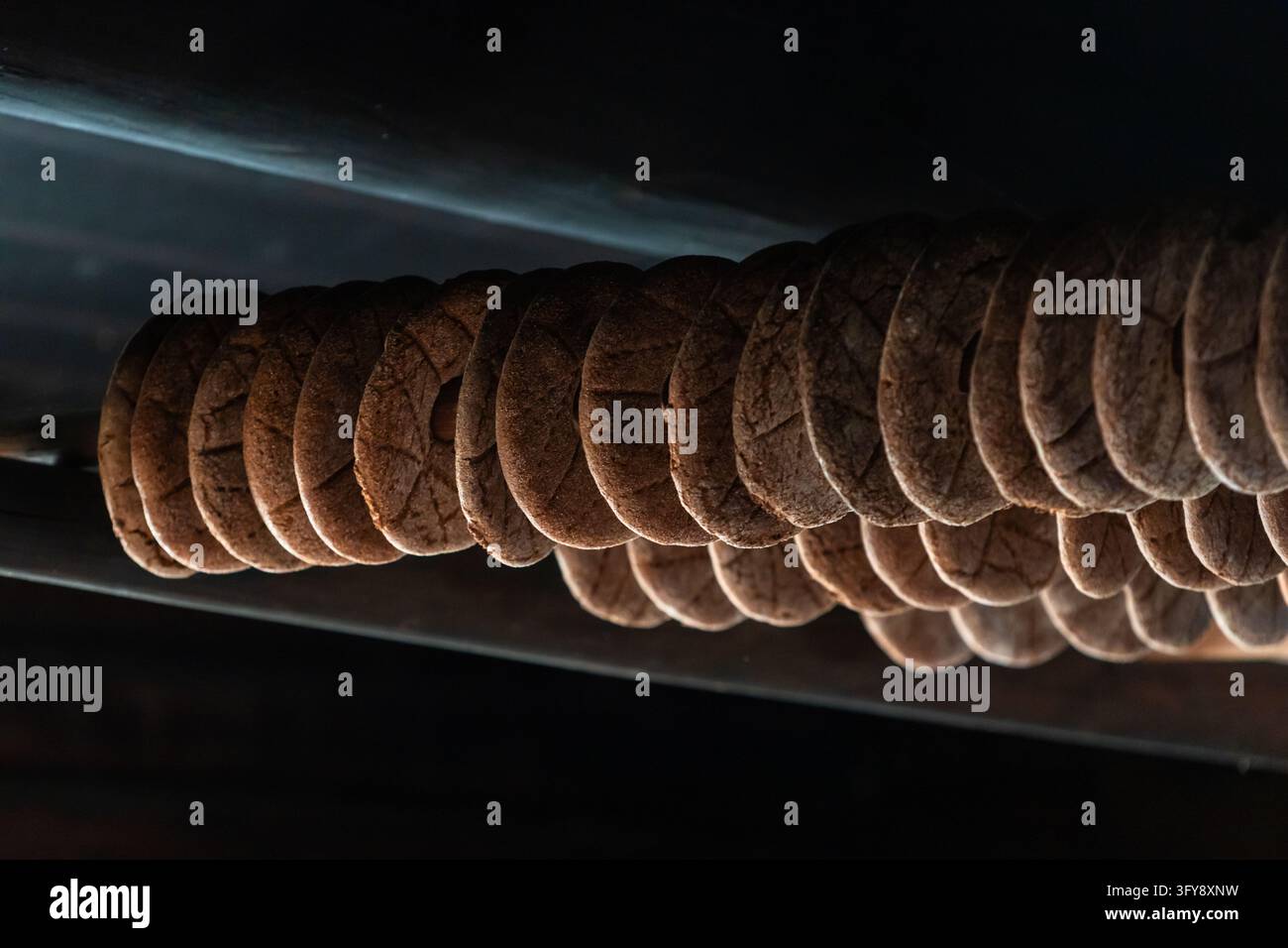 Pain de seigle finlandais traditionnel avec un trou au milieu, connu sous le nom de reikaleipa, suspendu en rangées sur des poteaux en bois pour sécher et fumer à l'intérieur, mettant en valeur un he Banque D'Images