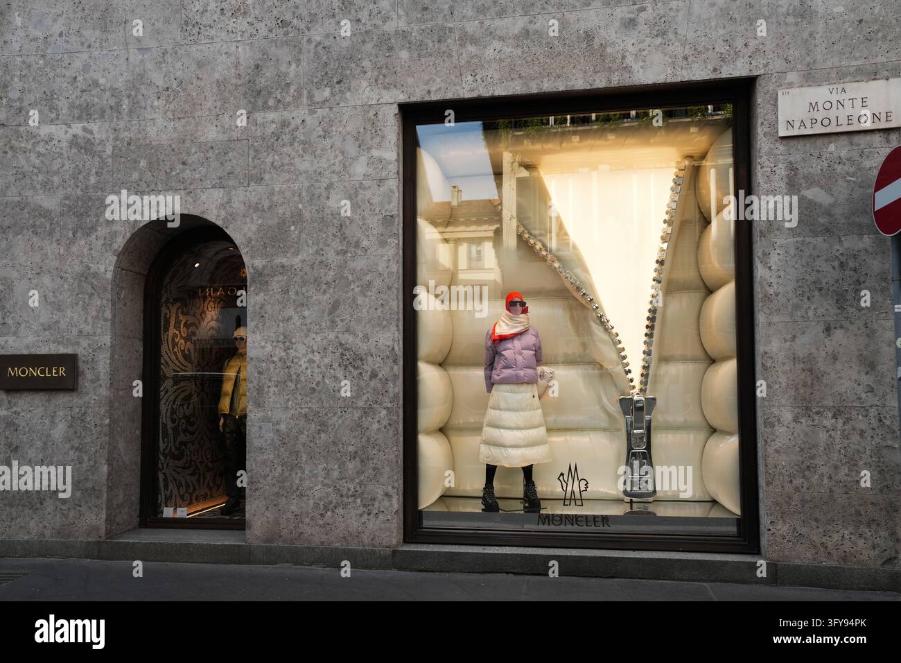 Milan, Italie - 15 octobre 2026 : Façade de la boutique Moncler avec une vitrine présentant une veste matelassée et un panneau de signalisation routière Banque D'Images