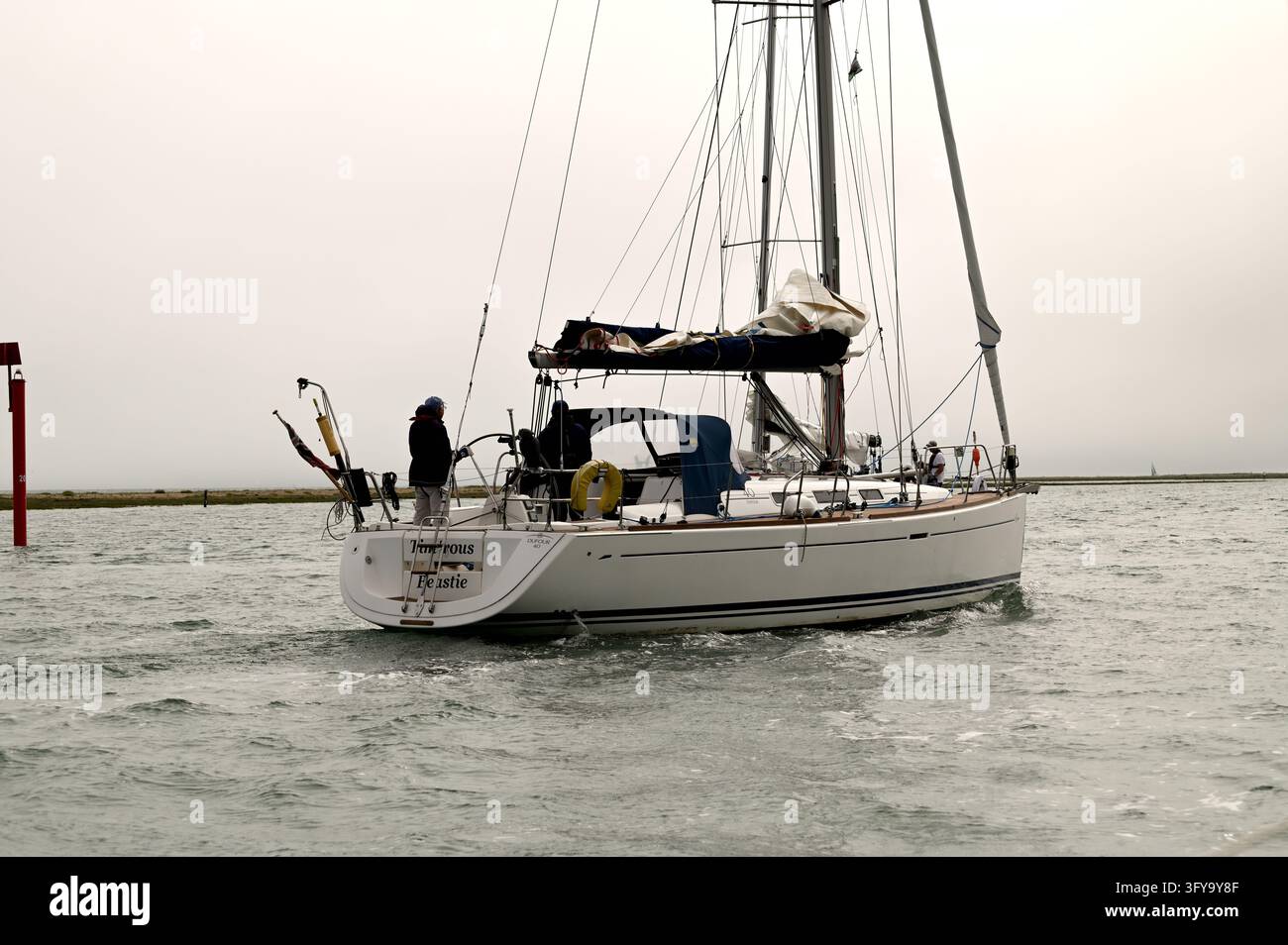 Équipage amenant un yacht de croisière avec pavillon rouge dans la rivière Beaulieu après une journée de navigation, Hampshire, Royaume-Uni, 20 juin 2026 Banque D'Images
