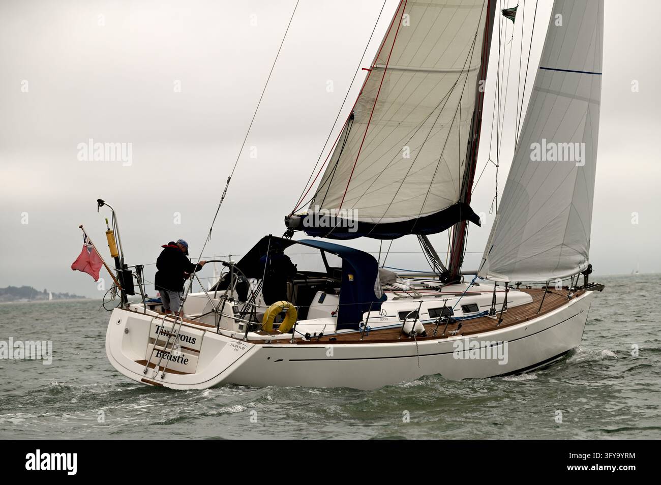 Équipage d'un yacht de croisière arborant un pavillon rouge naviguant sur le Solent au large de Cowes, Île de Wight, Royaume-Uni, le 20 juin 2026 Banque D'Images