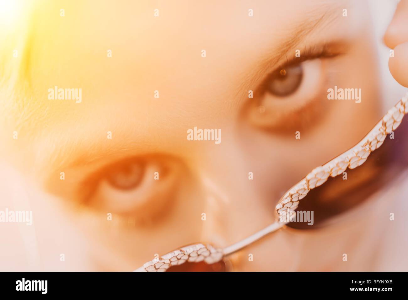 Yeux lunettes portrait Gros plan d'une femme regardant à travers des cadres de mode élégants avec un effet de lumière chaude et un éclairage artistique Banque D'Images