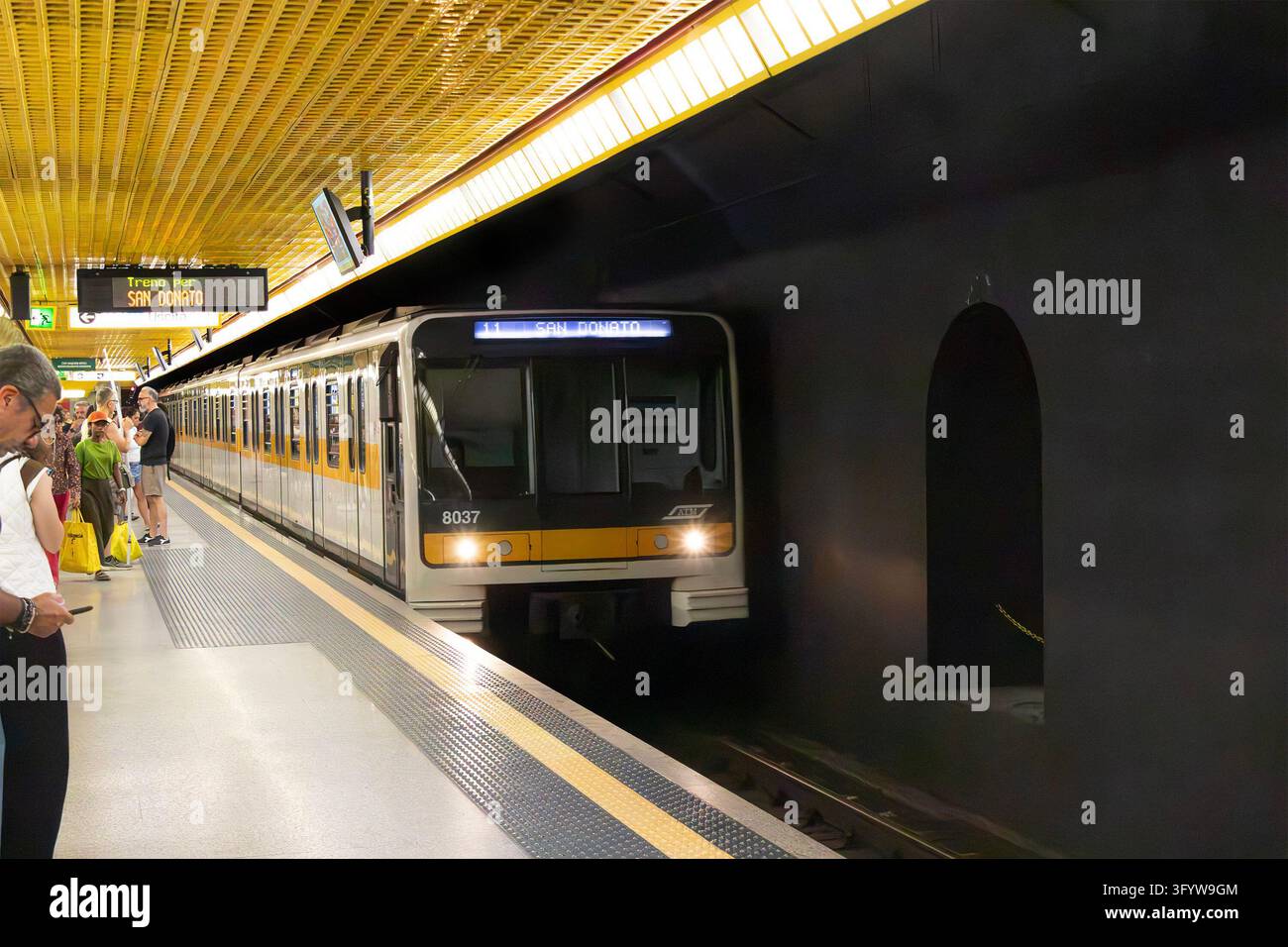 Train de métro jaune et blanc arrivant sur le quai de la station du métro de Milan, en Italie Banque D'Images