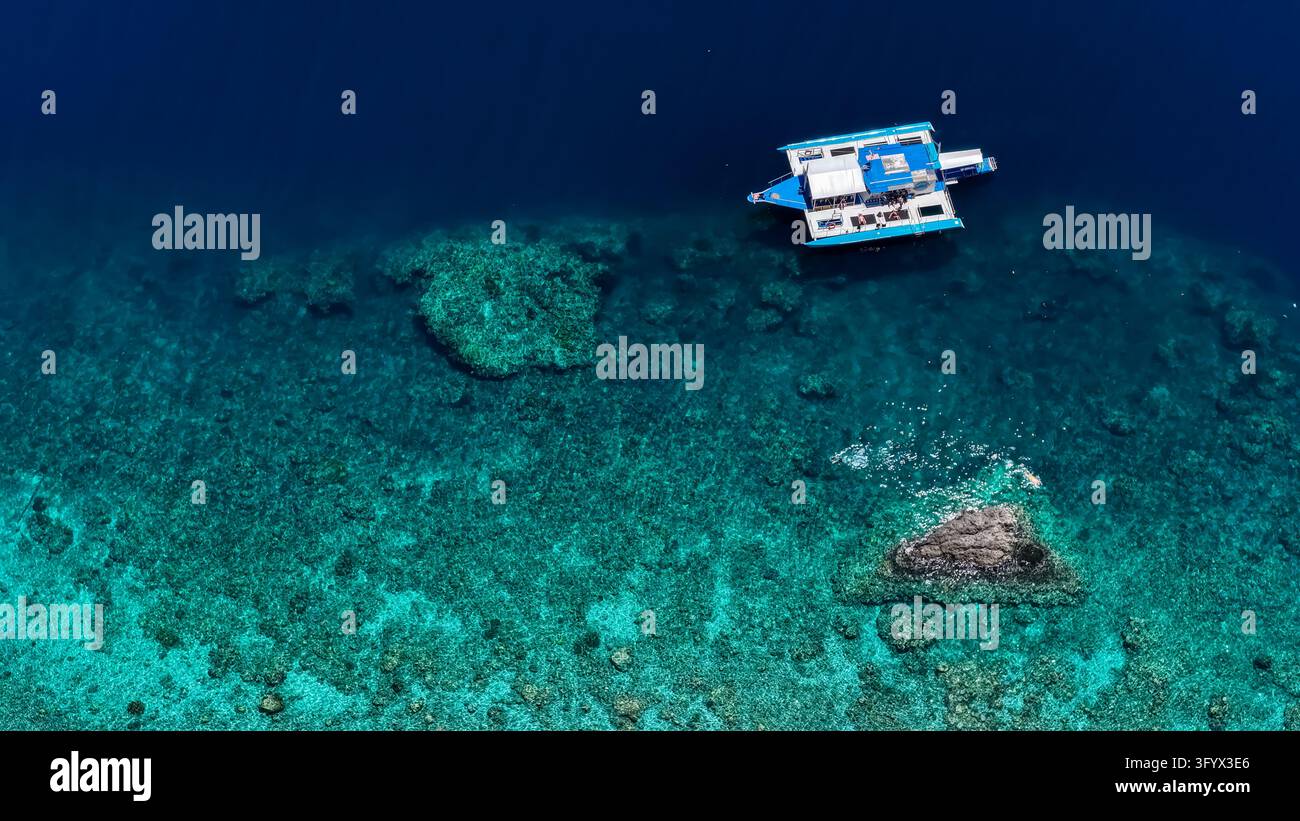 Vue aérienne d'un catamaran flottant dans une eau turquoise claire au-dessus d'un récif corallien vibrant dans le sud de Leyte, aux Philippines Banque D'Images