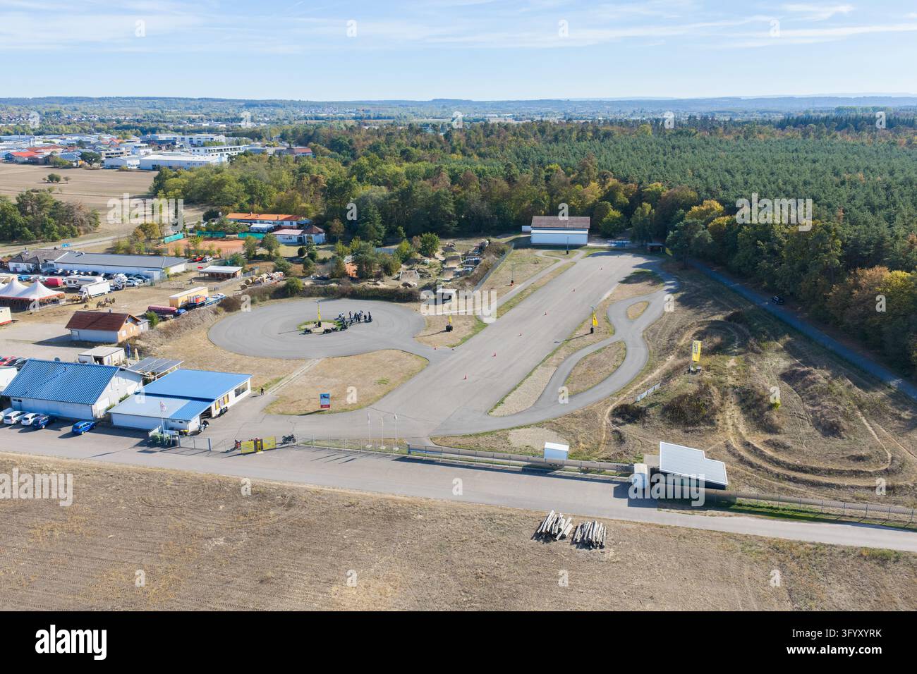 Vue aérienne du Centre de sécurité pour motos avec une piste d'entraînement pavée, une zone d'entraînement circulaire, une forêt environnante et des bâtiments à Bad Schonborn-Kr Banque D'Images