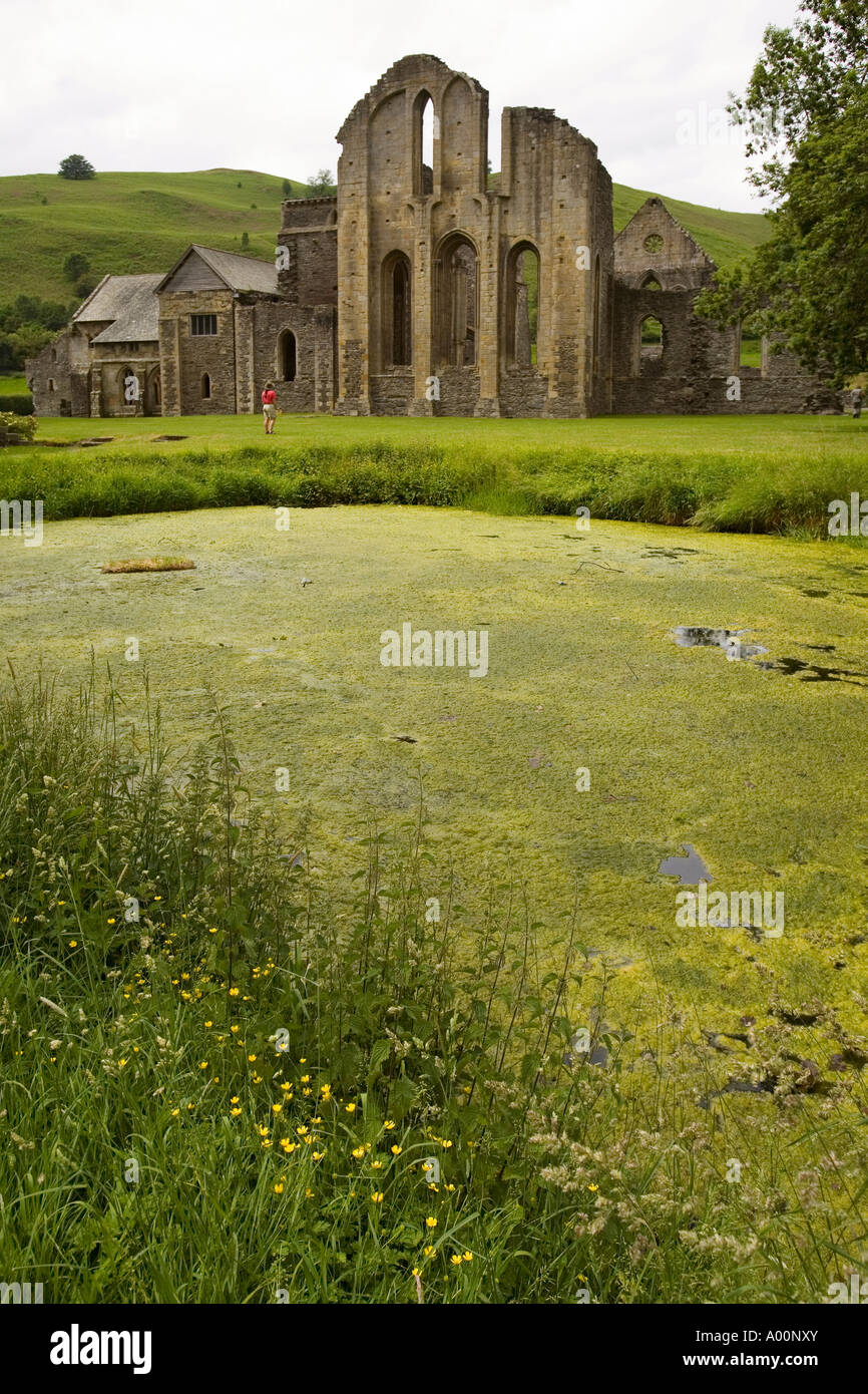 Étang monastique étouffées par les mauvaises herbes et femme debout à l'extrémité orientale de l'abbaye Valle Crucis Llangollen Wales UK Banque D'Images