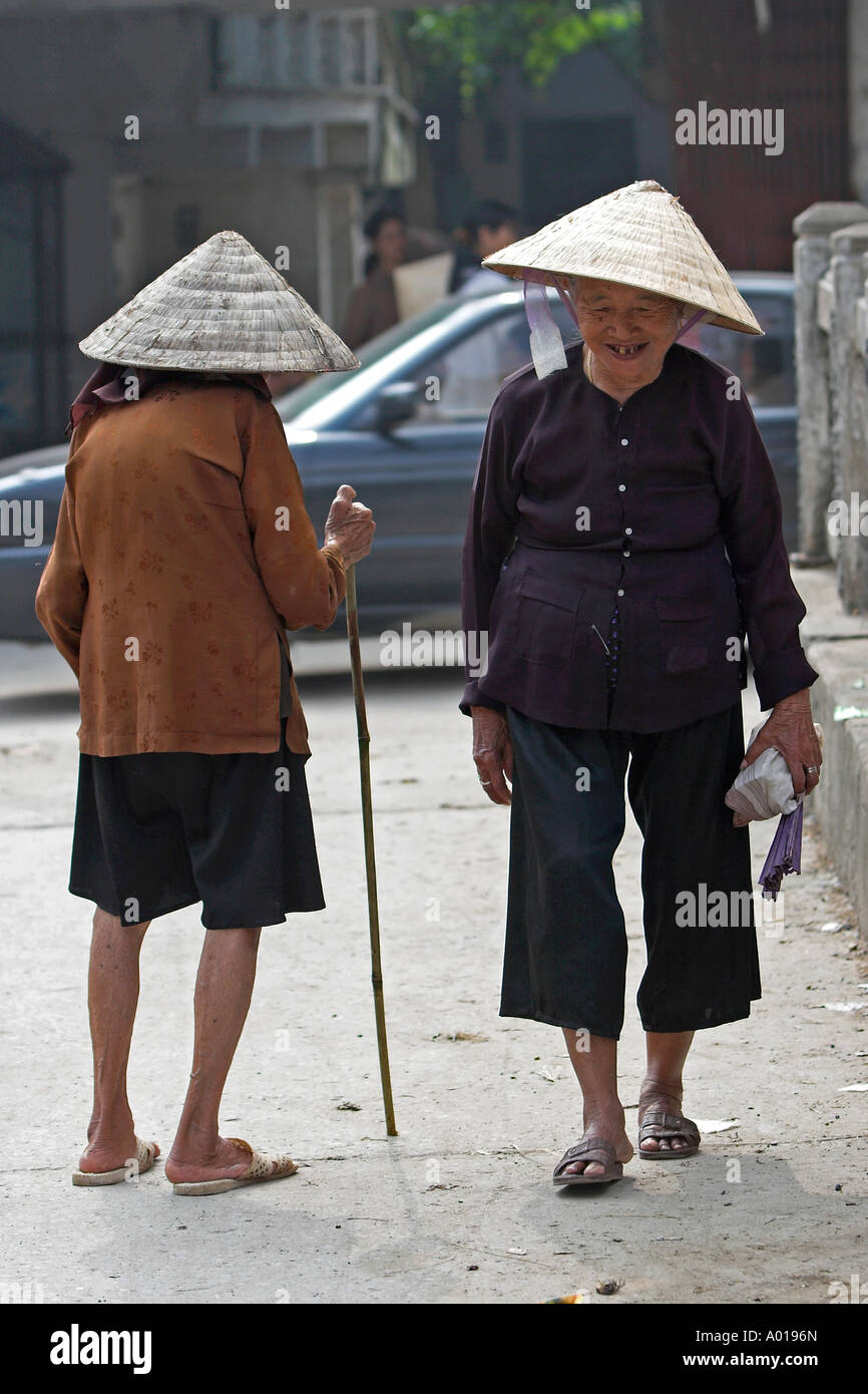 Deux personnes âgées femmes chapeau conique salue en passant sur le pont en Yen ville près de Pagode des parfums à l'extérieur du nord Vietnam Hanoi Banque D'Images