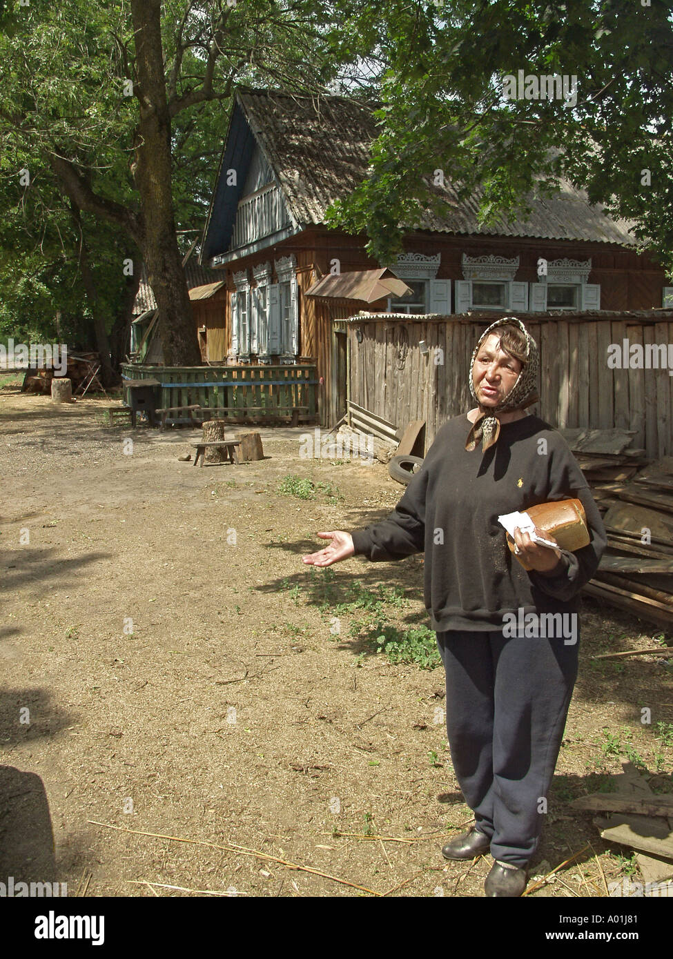 Survivants de Tchernobyl, 58 ans, femme, serrant miche de pain frais dans un bras en avant d'une rangée de maisons, zone d'exclusion de Tchernobyl, le Bélarus Banque D'Images