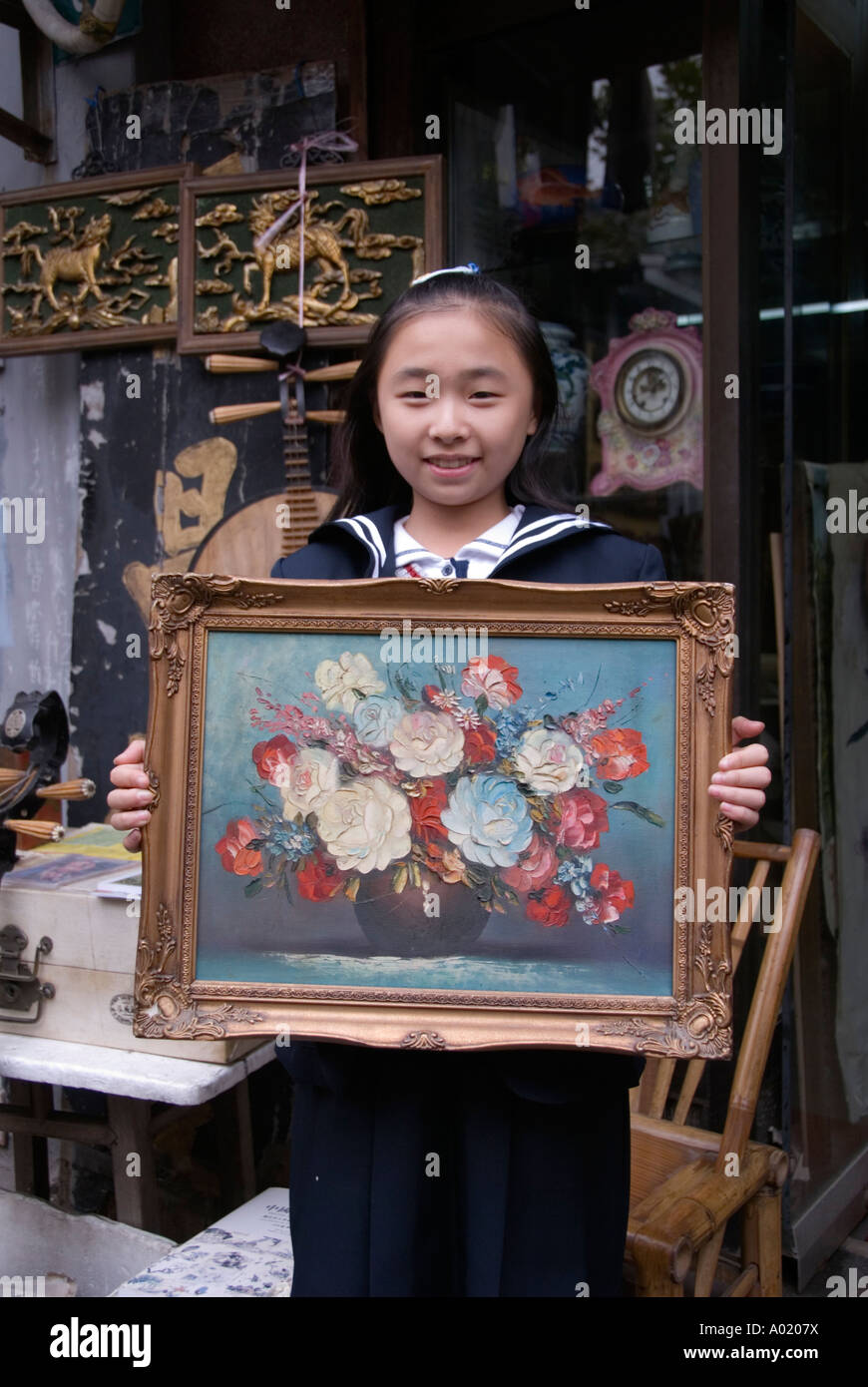 Young Girl holding Peinture de fleurs à l'extérieur de l'atelier à Dongtai Marché d'antiquités à Shanghai Banque D'Images