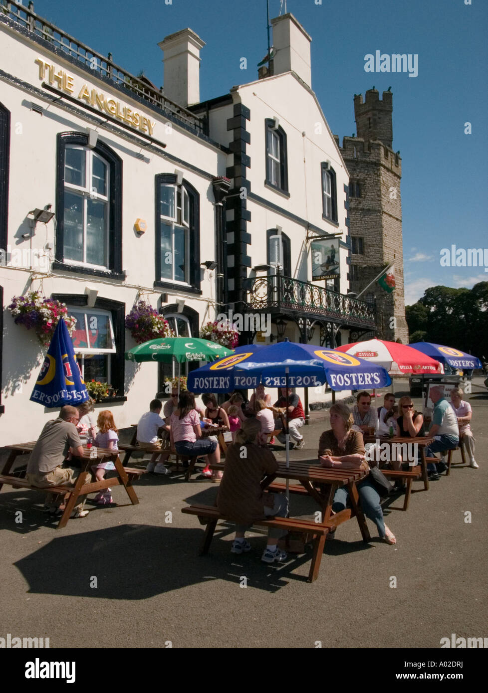 Des gens assis à des tables à l'extérieur de l''Anglesey pub près du château de Caernarfon Gwynedd le Snowdonia National Park North Wales UK Banque D'Images