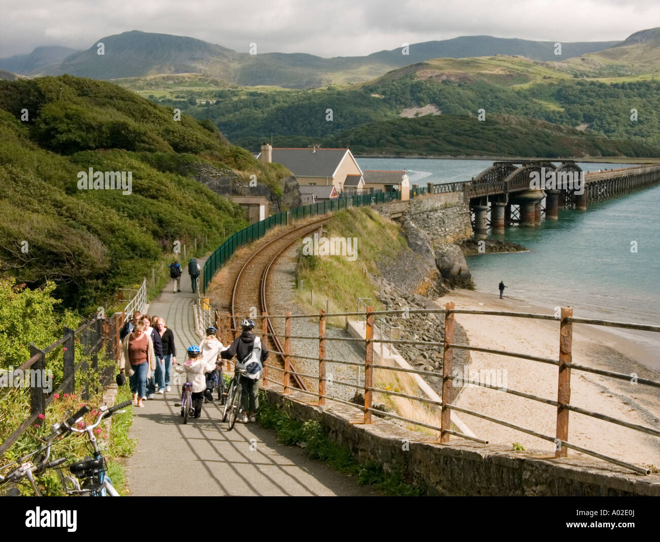 Les gens qui marchent la mawddach trail sentier à Barmouth, Gwynedd au nord du Pays de Galles, après-midi d'été au Pays de Galles UK, pont de chemin de fer en arrière-plan Banque D'Images