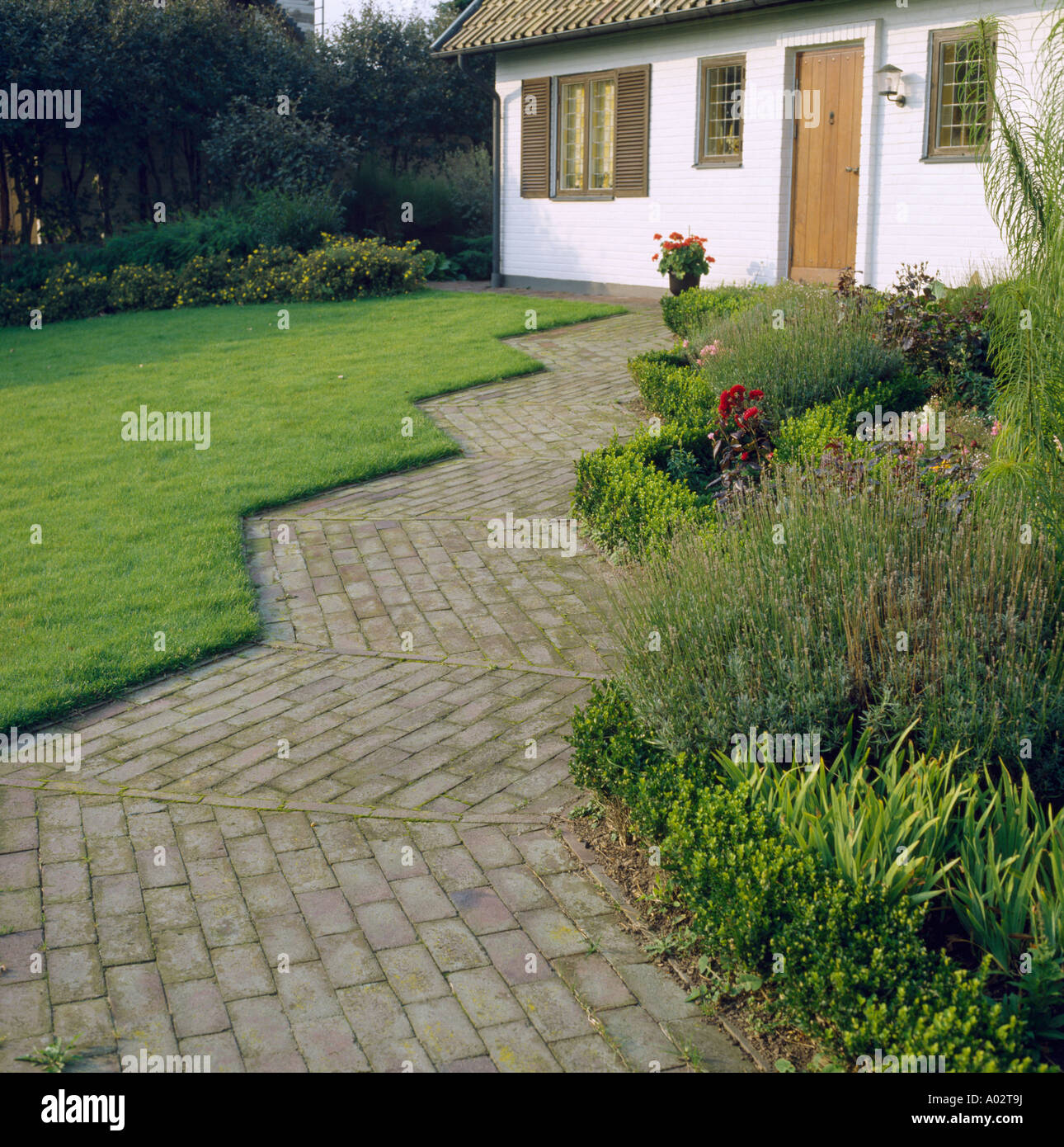 Ouvert chemin en zig zag à côté des frontières et étroitement cropped pelouse au jardin bien entretenu de la petite maison blanche Banque D'Images