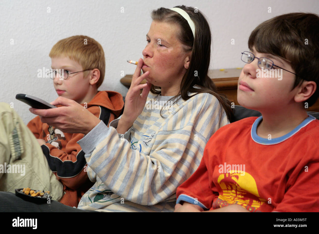Mère qui fume en regardant la télévision avec ses enfants Banque D'Images