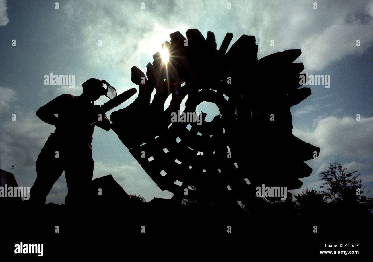 Bois recyclé transformé en sculpture de l'homme à hard hat avec tronçonneuse. Banque D'Images