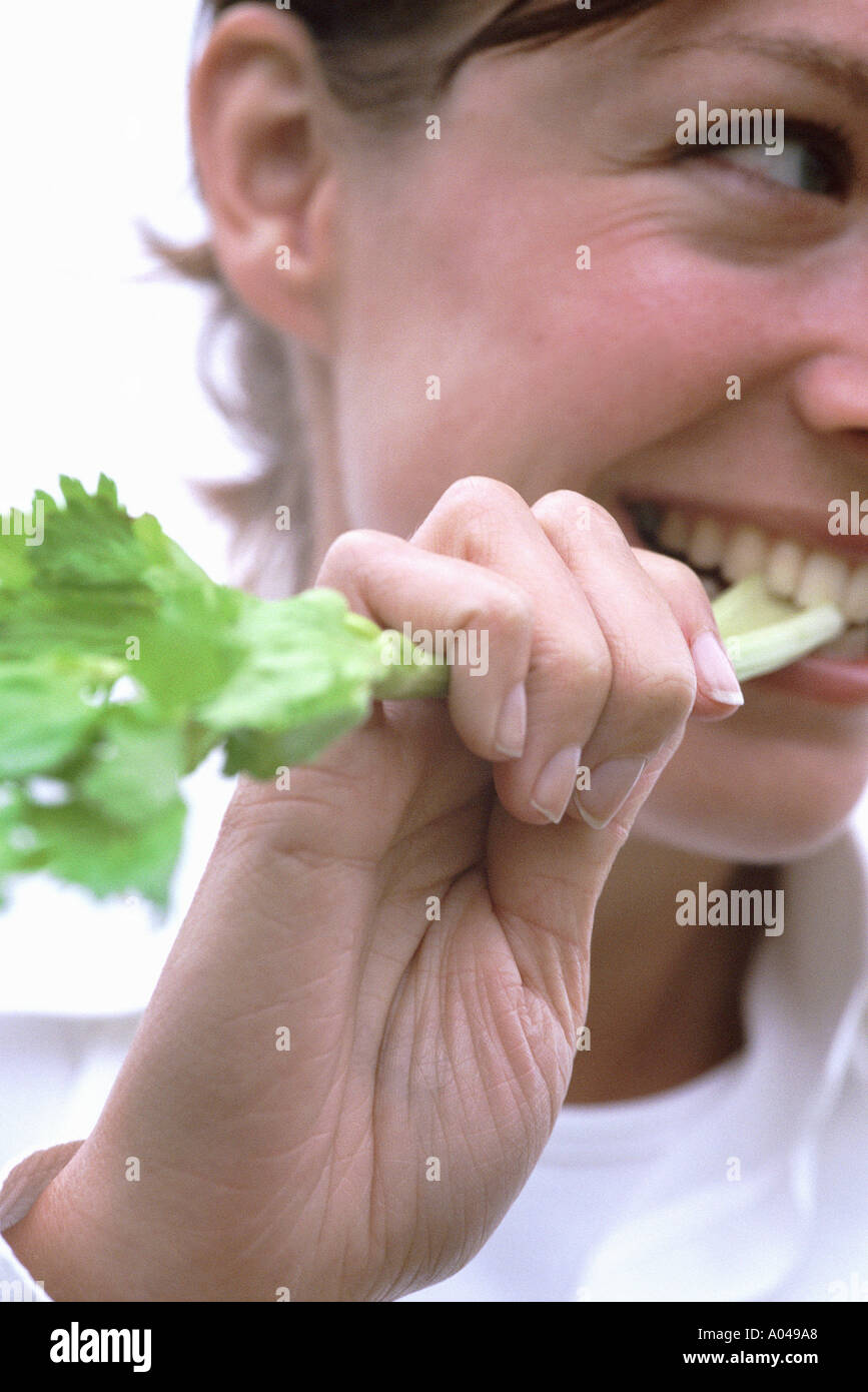Candid portrait of a young woman eating céleri Banque D'Images