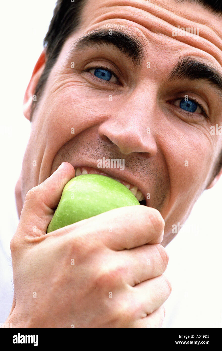 Close up portrait of a young man eating an apple Banque D'Images
