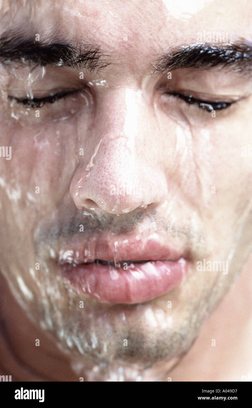 Portrait d'un jeune homme avec de l'eau couler sur son visage les yeux fermés Banque D'Images