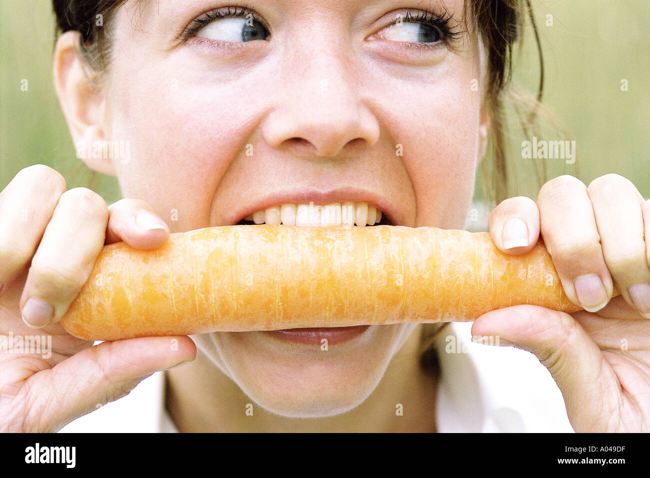 Close up portrait of young woman biting dans une carotte Banque D'Images