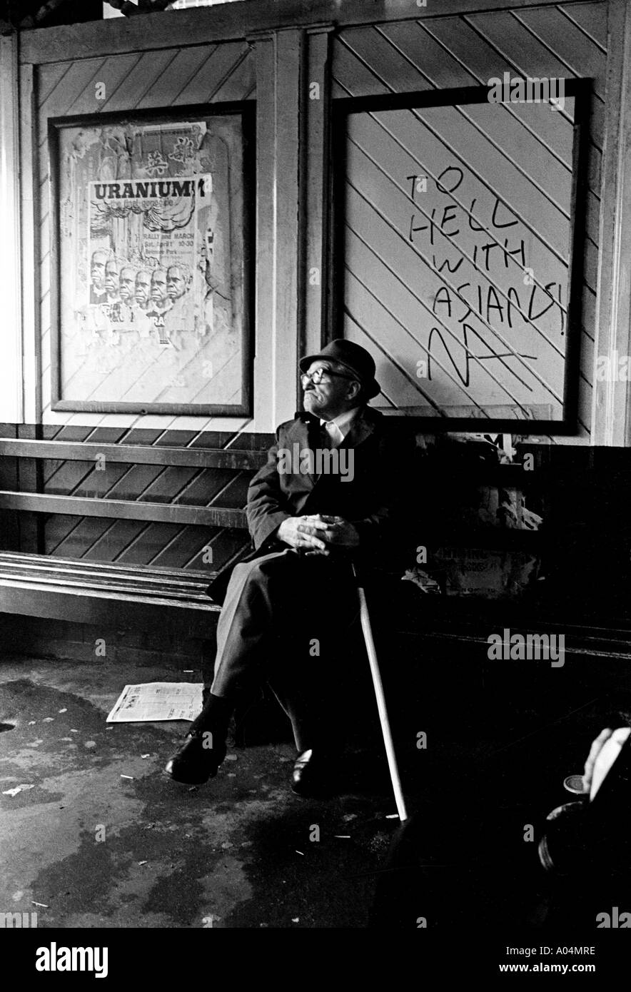 Un homme blanc âgé avec un bâton de marche assis dans un Abri en bus avec graffiti racial près de Circular Quay Sydney Australie 1977 Banque D'Images