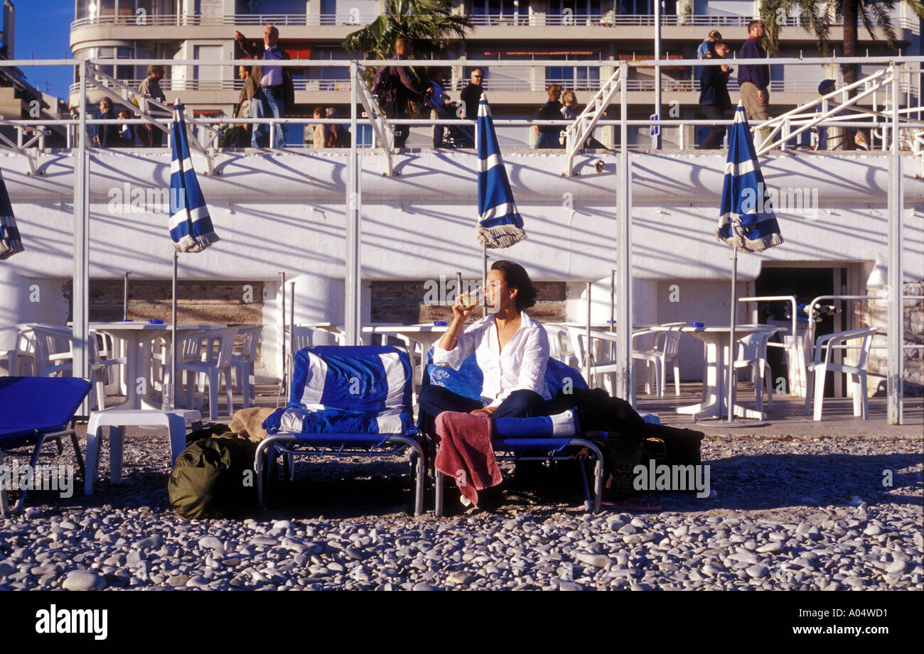 Une Femme buvant pernod sur la plage de Nice France avant de prendre l'avion à la fin d'une maison de vacances Banque D'Images