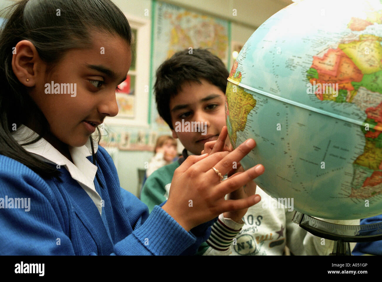 Les élèves Indiens asiatiques/looking at globe au cours de géographie de la classe. Banque D'Images