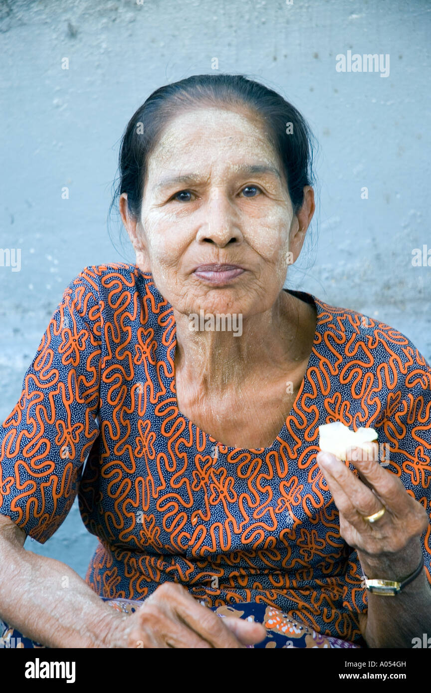 Femme portant thanakha manger par un mur, Yangon, Myanmar Banque D'Images