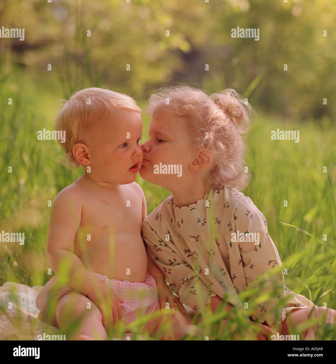Bebe Fille Embrasser Son Petit Frere Sur La Joue Alors Qu Il Etait Assis A L Exterieur Sur Une Couverture Dans L Herbe Photo Stock Alamy