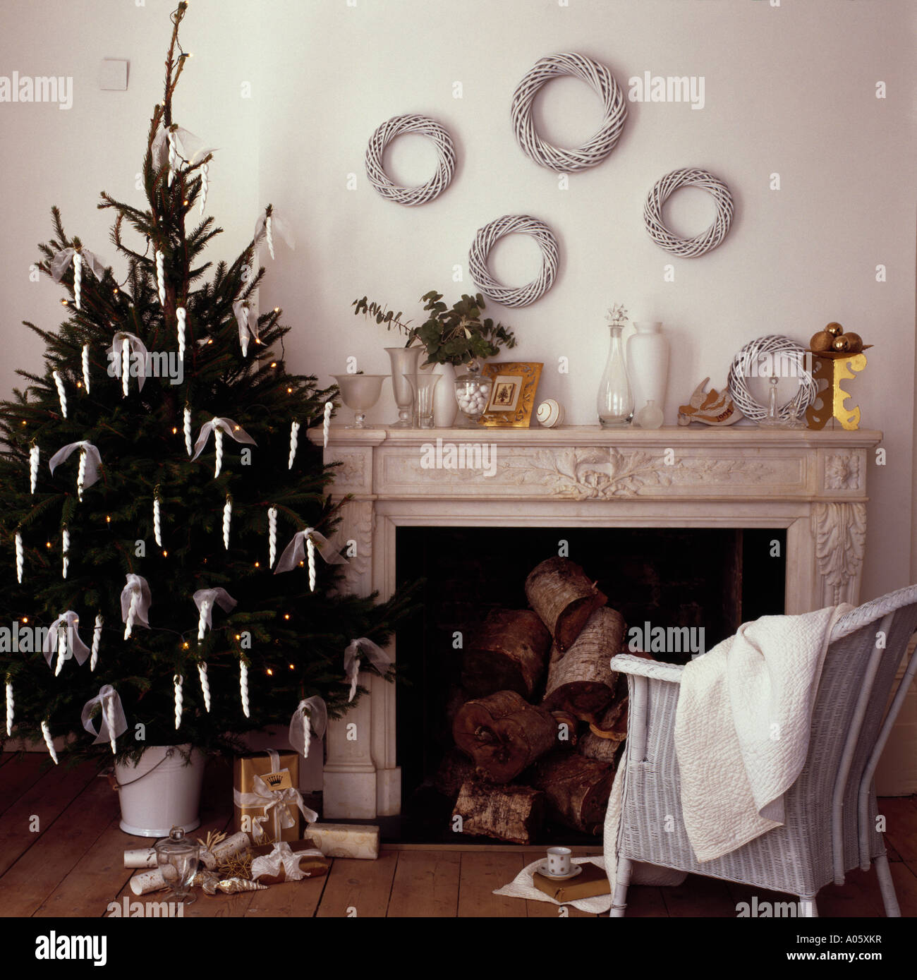 Arbre de Noël avec des décorations à côté de la cheminée de marbre blanc et blanc chaise en osier Banque D'Images